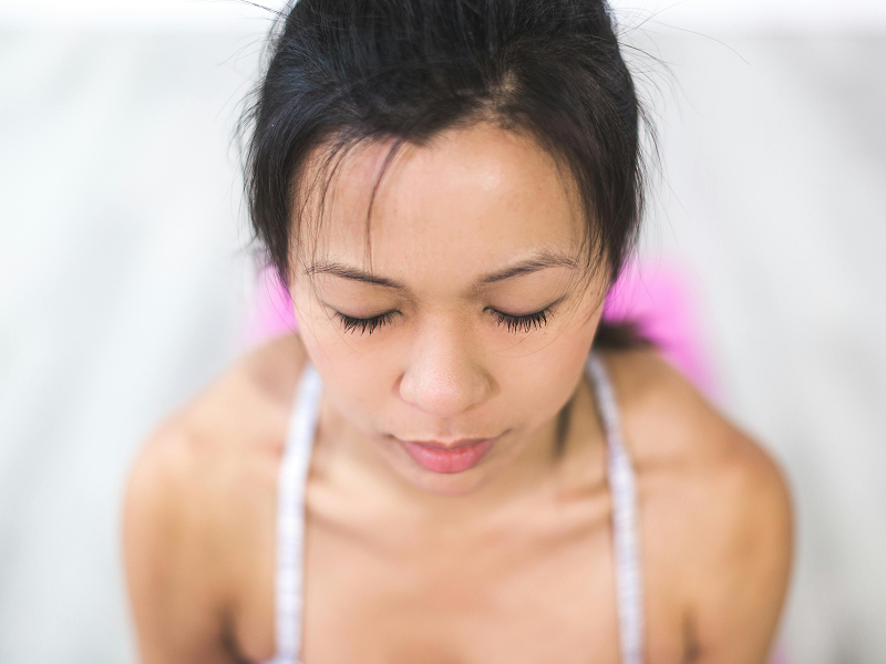 A top-down, close-up view of a woman with her eyes closed, showing clear skin and natural features.